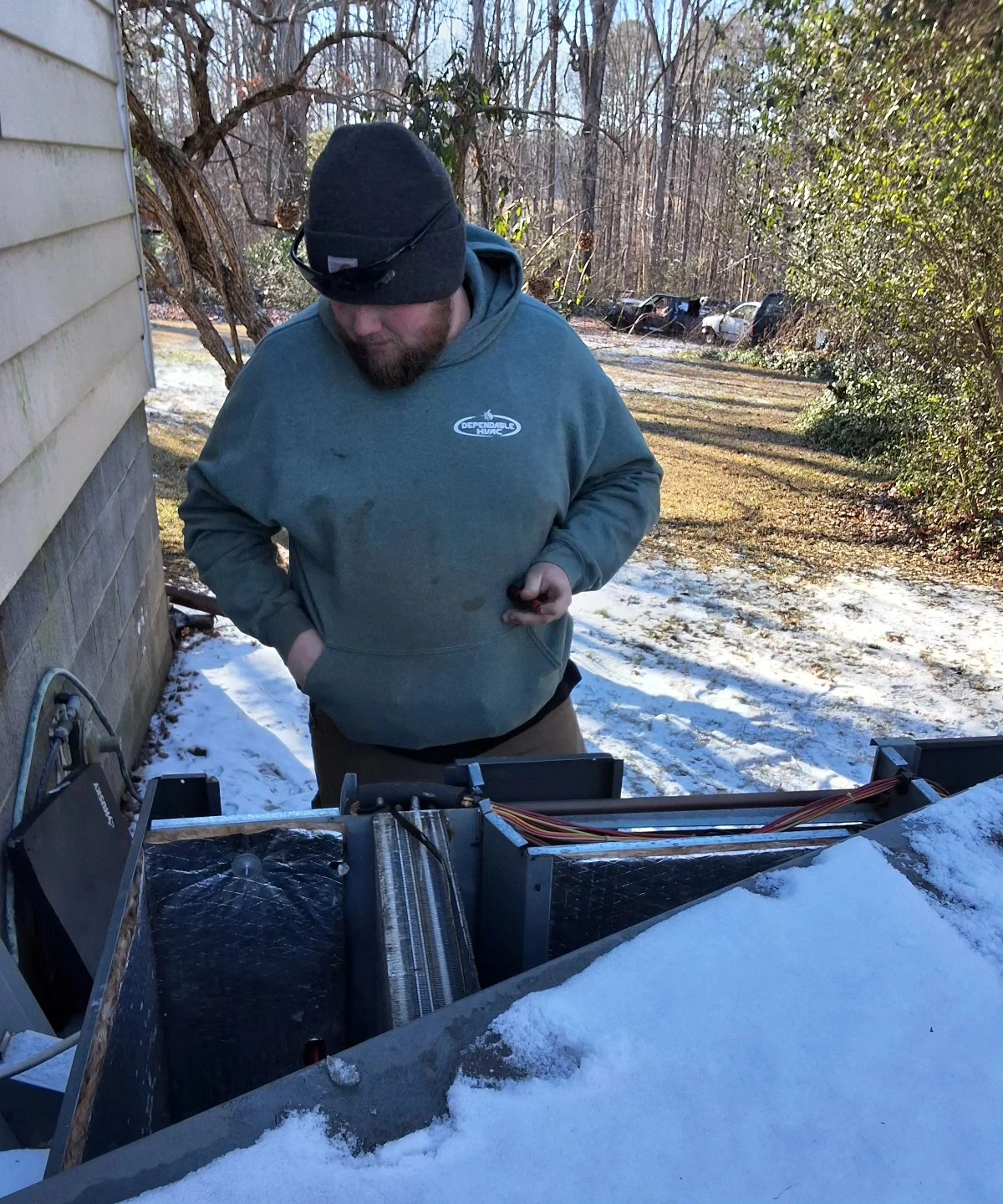 HVAC technician servicing outdoor unit in winter